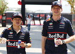 Max verstappern and Yuki Tsundo walking holding Red Bull cans and speaking