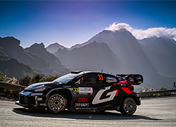 a Toyota WRC racing car parked in formnt of mountains