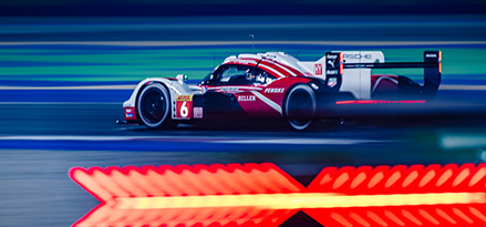 Pistte kırmızı ve beyaz Porsche yarış arabası