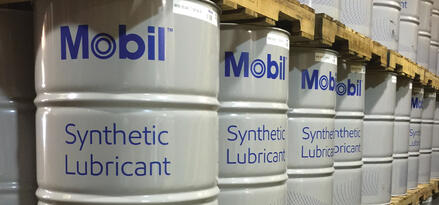 Mobil™ Synthetic Lubricant varilleri, düzenli bir depo koridorunda paletler üzerine istiflenmiş.